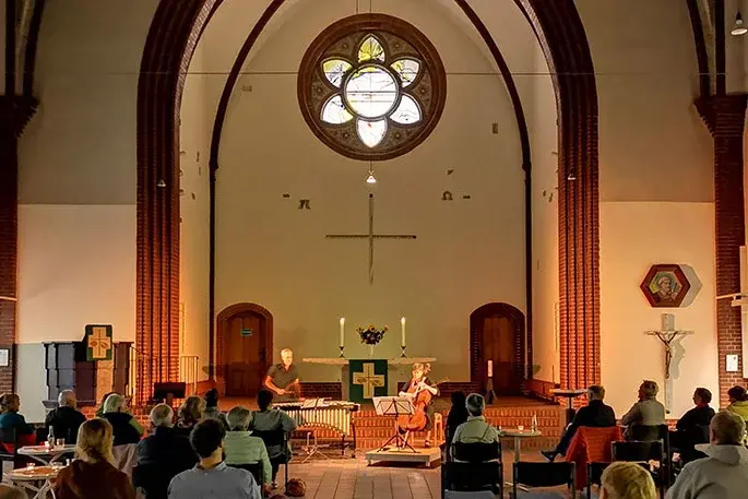 Konzert mit Oli Bott & Anna Carewe vor dem Altar der Petruskirche mit Fensterrosette im Hintergrund